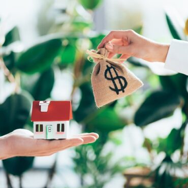 cropped shot of people exchanging sackcloth bag with dollar sign and house model